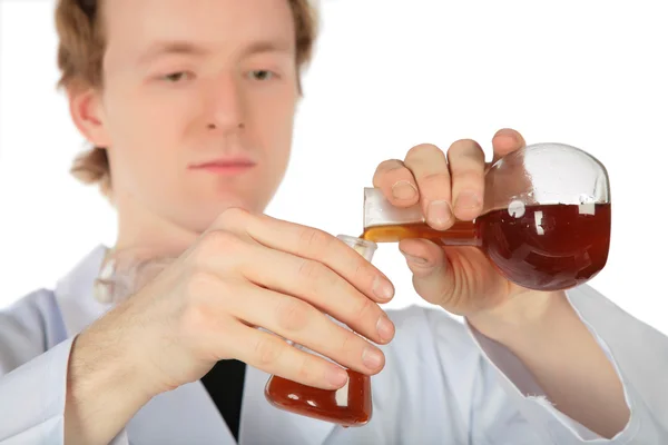 化学者は別の 1 つのフラスコからの茶色の液体を注ぐ — ストック写真