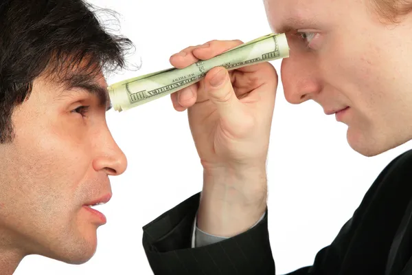 Um homem de negócios olha para o outro através de um pequeno tubo de dólar — Fotografia de Stock