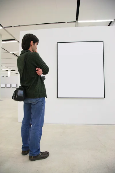 Visitante mira en el marco en la sala de exposición —  Fotos de Stock