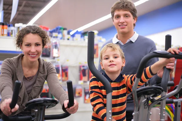 Ouders met zoon op sporttrainingen apparaat in winkel — Stockfoto