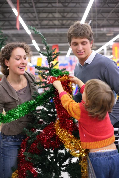 Los padres con el niño compra árbol de Navidad con decoraciones — Foto de Stock