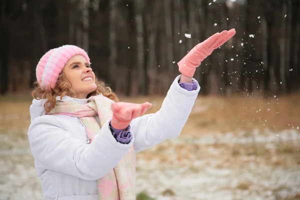 Young beauty girl in wood in winter catches snowflakes — Stock Photo, Image