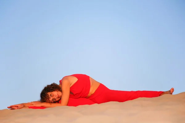 Mujer joven en rojo se encuentra en la arena — Foto de Stock