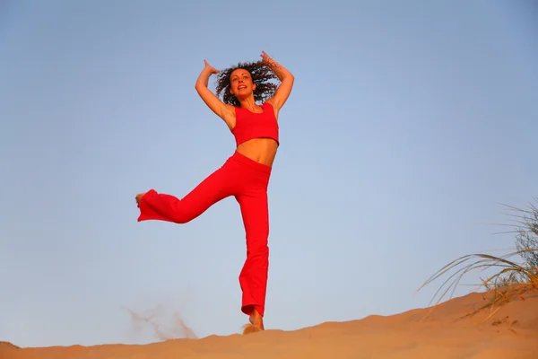 Mujer joven en rojo corre sobre la arena — Foto de Stock