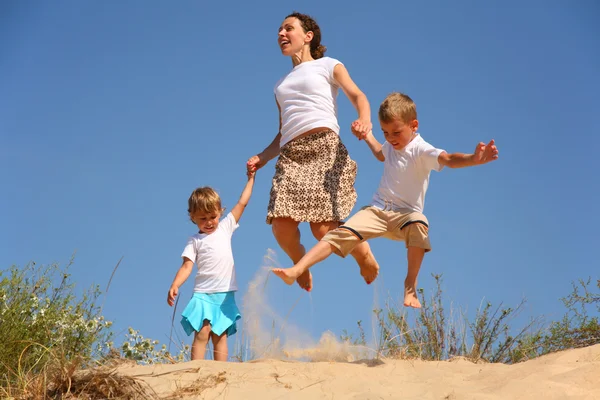 Mother with children jumping on sand — Stock Photo, Image