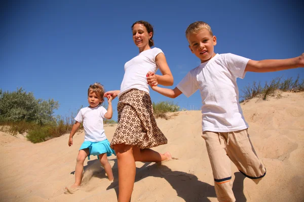 Мати з дітьми біжить на піску — стокове фото