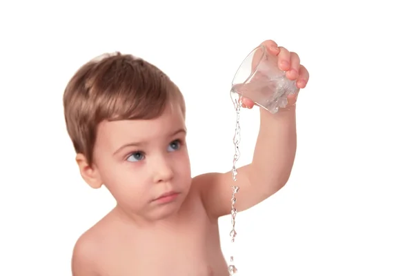 Child pours out water from glass — Stock Photo, Image