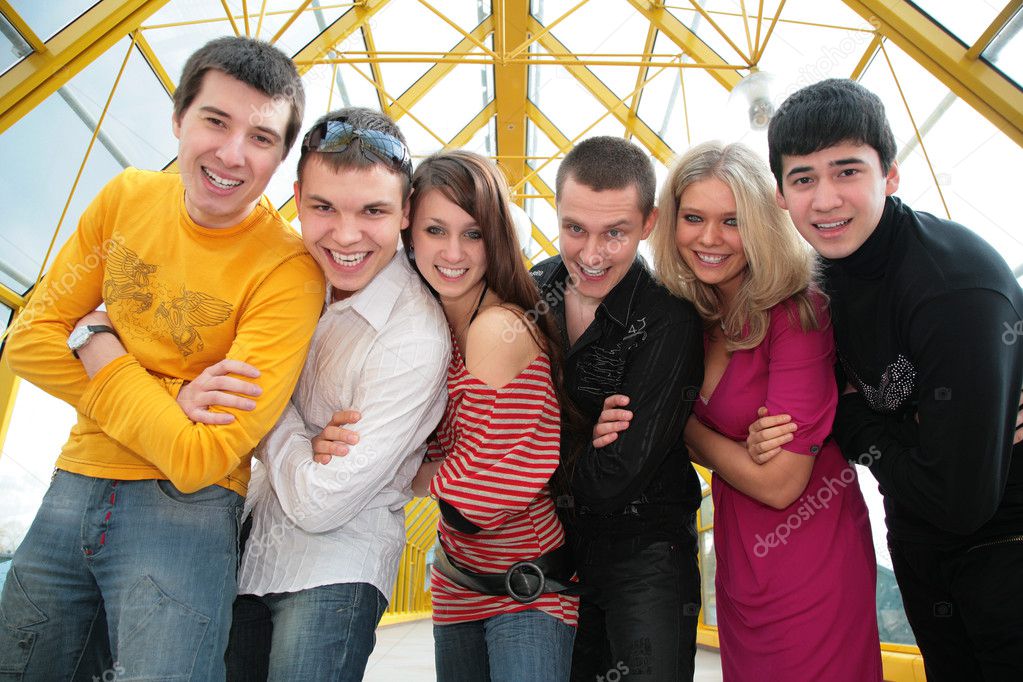 Group of young friends on footbridge look on you