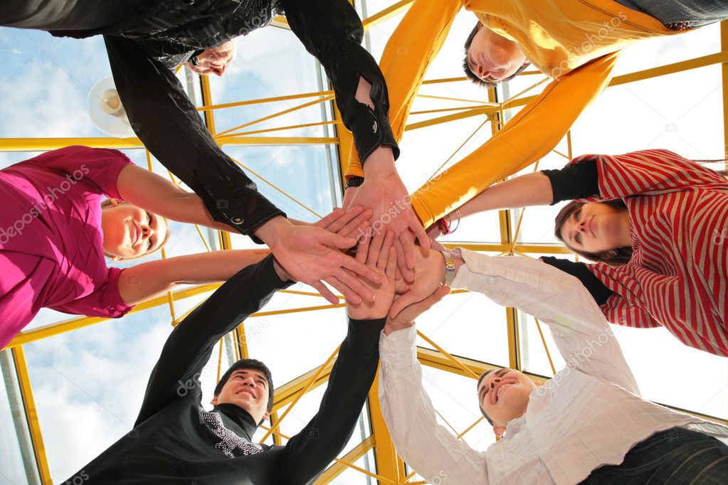 Six friends joining hands low angle view
