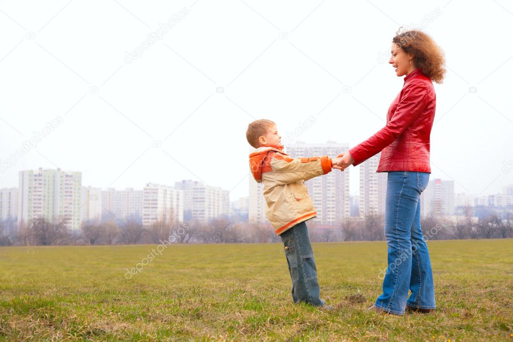 Mother and son stand outdoor and look on each other