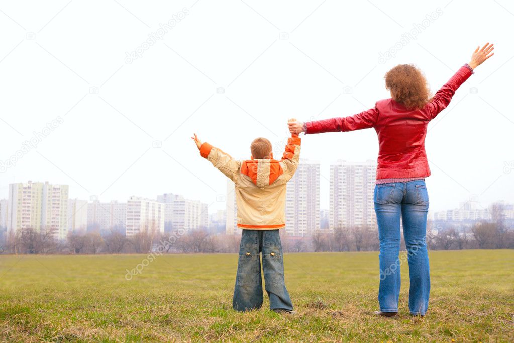 Mother and son stand outdoor with lifted hands