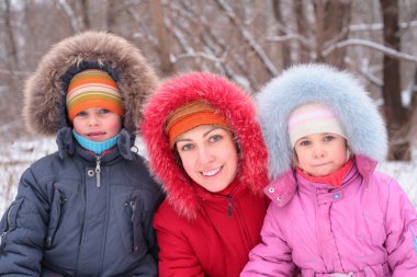 Mother with children in wood in winter clipart