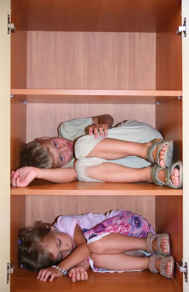 Duas crianças dormem em prateleiras no armário — Fotografia de Stock