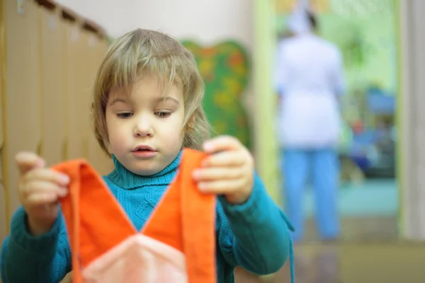 Девочка в детском саду с платьем в руках — стоковое фото
