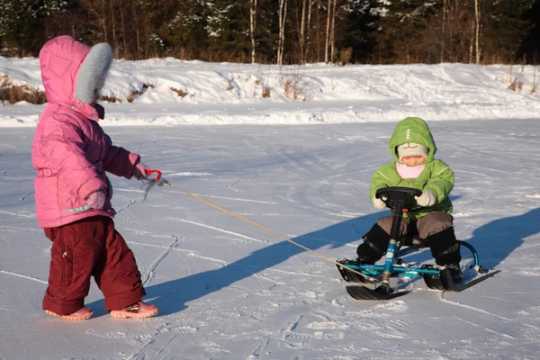 Criança puxa outro em scooter de neve — Fotografia de Stock