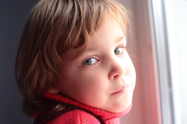 Маленькая заботливая девочка у окна — стоковое фото