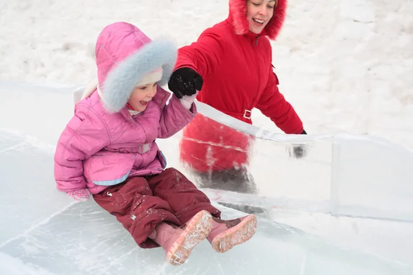 Girl rolls down on ice slope with mother — Stock Photo, Image