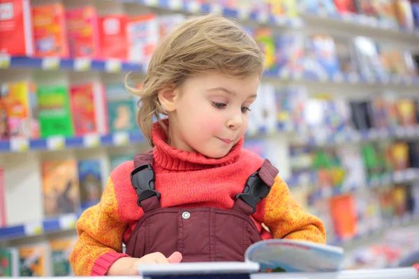 Маленькая девочка в книжном магазине — стоковое фото