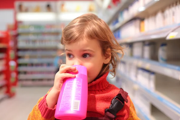 Menina na loja com garrafa de plástico — Fotografia de Stock
