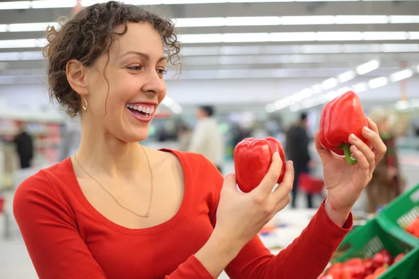Молодая женщина в магазине с красным сладким перцем — стоковое фото