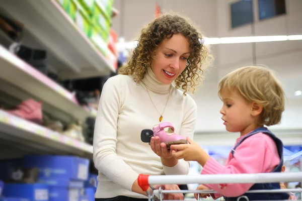 Moeder met dochter kiezen schoeisel in winkel — Stockfoto