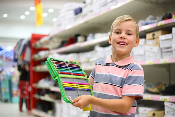 Jongen met kleur potloden in winkel — Stockfoto
