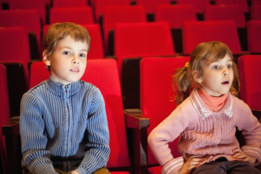 Boy and little girl sitting on armchairs at cinema, girl has op clipart