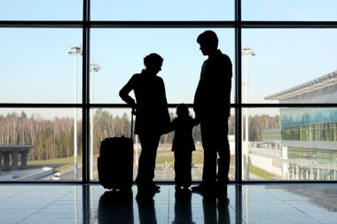 Silhouette of mother, father and daughter with luggage standing clipart