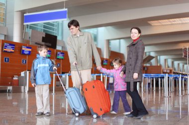 Family with suitcases walking in airport hall clipart