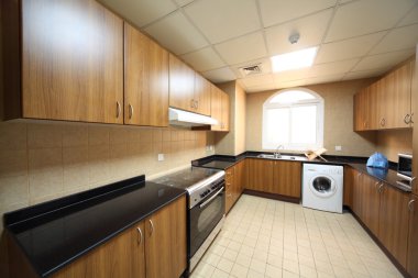 Kitchen with brown cupboards, washingmachine and cooker clipart