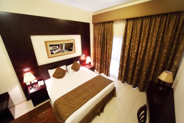 beyaz duvarları, kahverengi perde ve büyük Çift Kişilik Yatak görünümü ile yatak odası