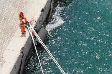 Two workers in uniform moor a ship at summer day view from above clipart