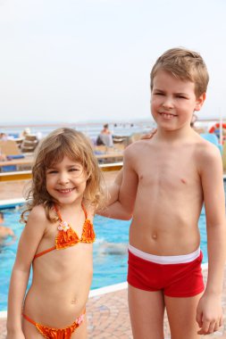 Caucasian little girl and boy standing on cruise ship and smilin clipart