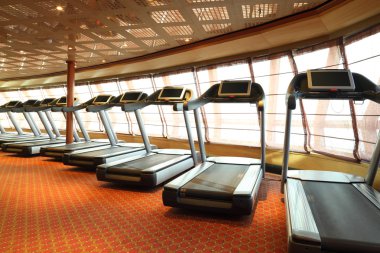 Large gym hall with treadmills near windows in cruise ship clipart