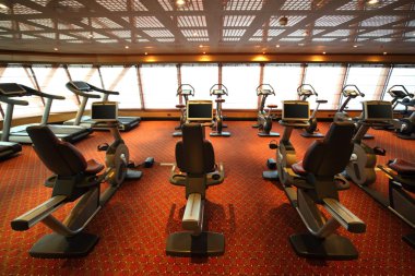 Large gym hall with exercise bicycle in cruise ship view from ba clipart