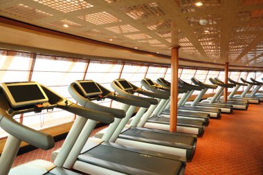 Large gym hall with treadmills near windows in cruise ship gene clipart