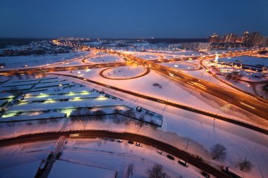 Evening winter cityscape with big interchange and lighting colum clipart