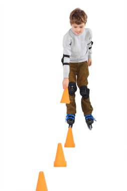 Little boy with cone in hand rollerblading near orange cones loo clipart