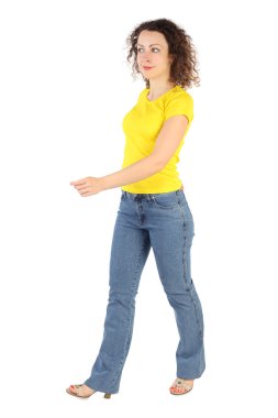 Young attractive woman in yellow shirt and jeans walking left is clipart