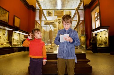Boy and little girl at excursion in historical museum near exhib