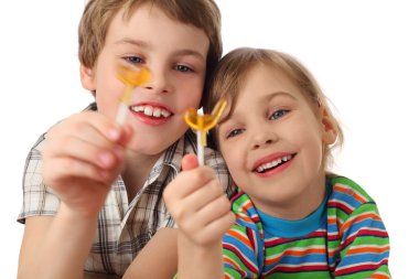 Little boy and girl holding lollipops ,looking on it and laughin clipart