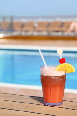 Cocktail with fruits in glass on ship deck floor near swimming p clipart