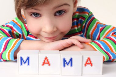 Little girl plays with cubes and puts it together in word 