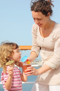 Mother and daughter standing on cruise liner deck, mother holdin clipart