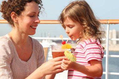 Mother and daughter standing on cruise liner deck, mother holdin clipart