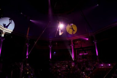 Circus performance with two trapeze gymnasts purple light clipart