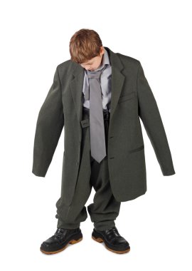 Little boy in big grey man's suit and boots looking at floor iso clipart