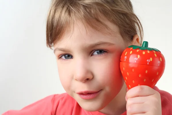 Маленька дівчинка в червоній сорочці тримає в руці пластиковий кухонний таймер — стокове фото
