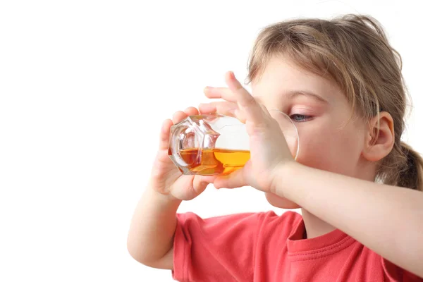 Маленькая девочка в красной рубашке держит стакан с соком для двух рук — стоковое фото