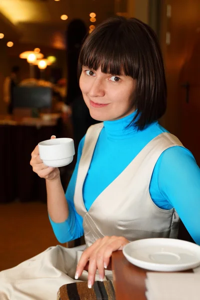 Wanita tersenyum duduk di kafe dengan cangkir — Stok Foto